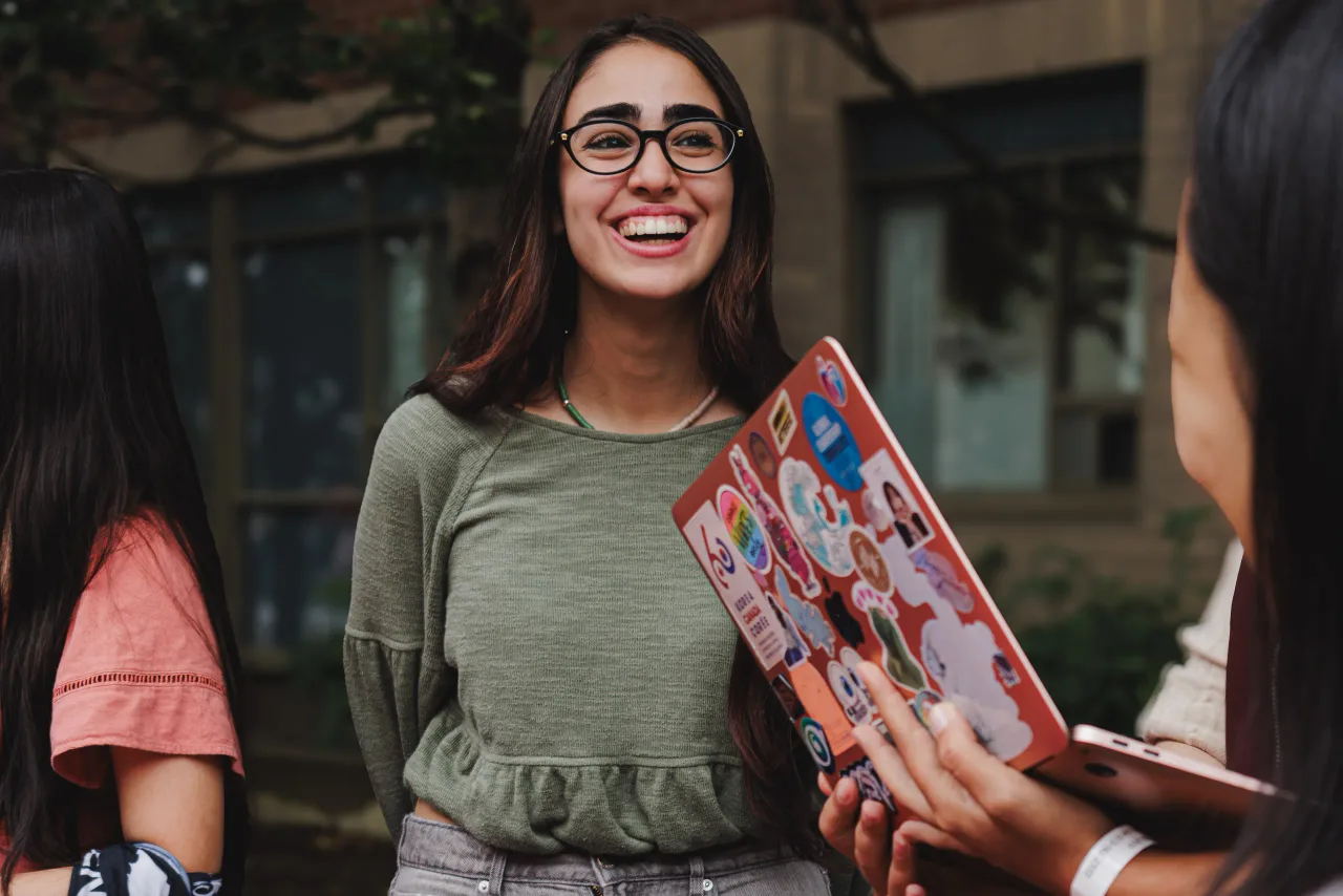 A student laughing while holding a sticker board at the club table